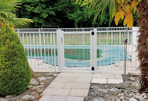 Barrière de piscine barreaudée sous main-courante et portillon. Pose sur dalle. RAL 9016.